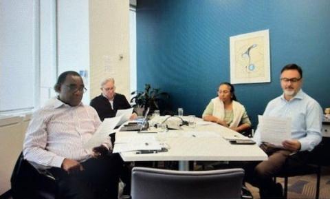 Partner council members gathered around a table with papers and laptop open