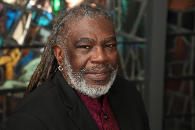 Michael Blair smiling, sitting in front of stained glass